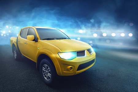 Four door yellow pickup truck with dark concrete on highwayの写真素材