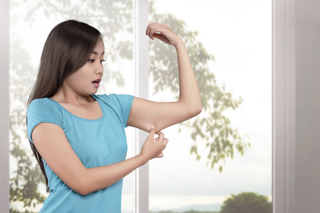 Young asian women weight loss on her arm with window glass backgroundの写真素材