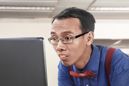 Asian nerdy businessman working using laptop at officeの写真素材