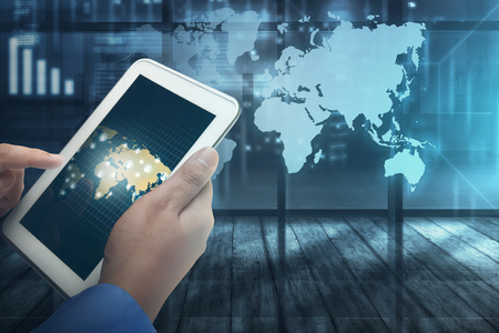 Businessman working on futuristic tablet computer with virtual world map on backgroundの写真素材