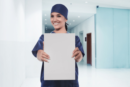 Happy asian woman nurse showing empty white board in a hospitalの写真素材