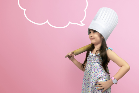 Asian cute girl in chef uniform with copyspace over pink backgroundの写真素材