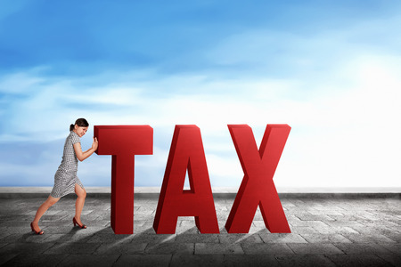 Young asian entrepreneur woman pushing a Tax word with blue sky backgroundの写真素材