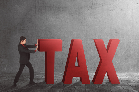 Asian businessman pushing away Tax text on urban streetの写真素材