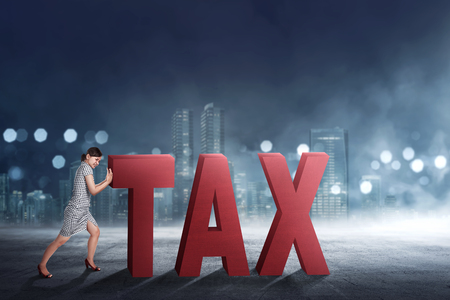 Beautiful asian business woman pushing away Tax text with cityscape backgroundの写真素材