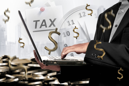 Businessman holding laptop with deadline for Tax payment on modern backgroundの写真素材
