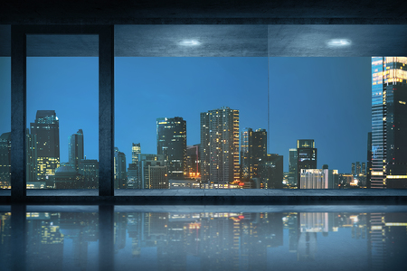 Empty office room with view of the city at nightの写真素材