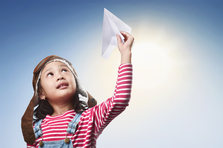 Happy asian kid with toy paper plane having fun at outdoorの写真素材