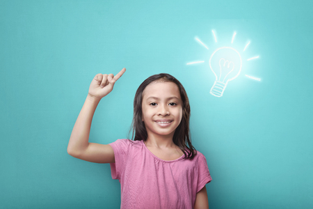 Clever asian child with bright idea symbol above her head over bright backgroundの写真素材