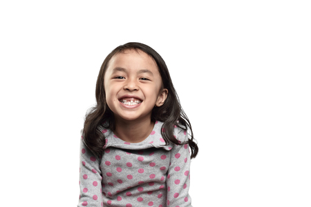 Smiling asian kid showing her missing tooth isolated over white backgroundの写真素材