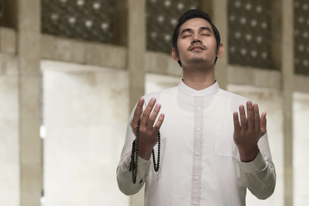 Handsome asian muslim man with beads praying to god in the mosqueの写真素材