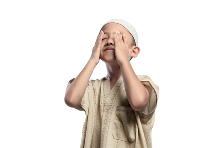 Little asian muslim kid with white cap praying isolated over white backgroundの写真素材