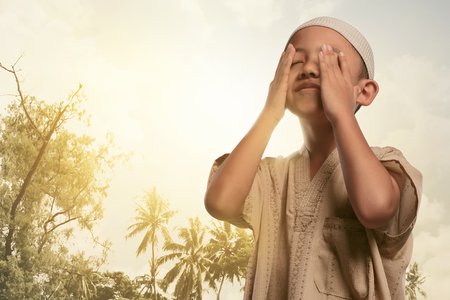 Religious asian muslim boy praying to god with sunset backgroundの写真素材