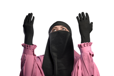 Young asian muslim woman wearing niqab praying to god isolated over white backgroundの写真素材