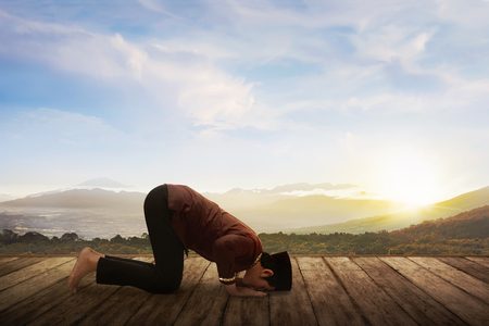 Asian muslim man in traditional dress praying with wooden floor on natureの写真素材