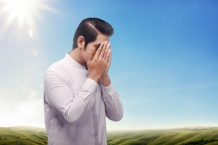 Religion asian muslim with solemn pray to god against blue sky backgroundの写真素材