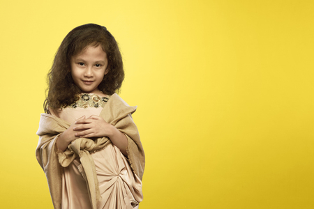Cheerful asian muslim child with traditional dress over yellow backgroundの写真素材