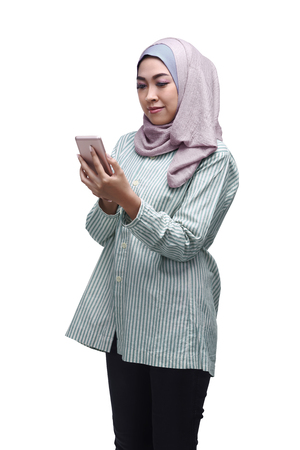 Beautiful asian muslim woman using mobile phone isolated over white backgroundの写真素材