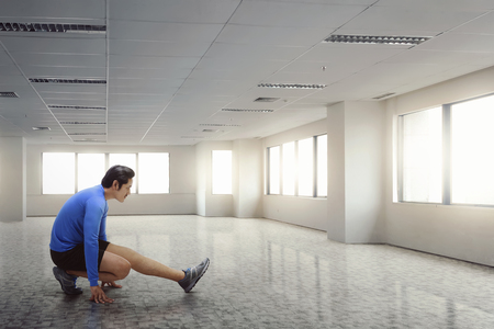 Fitness asian man stretching his legs after running exercise in the gymの写真素材