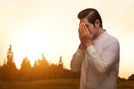 Asian muslim man with traditonal dress praying over sunset backgroundの写真素材