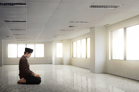 Young asian muslim man with traditional dress praying indoorの写真素材