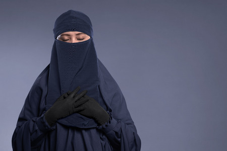Young asian muslim woman wearing niqab with peaceful expression over dark backgroundの写真素材