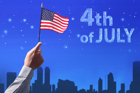 People hand holding the flag of USA celebrating 4th of July over night scene backgroundの写真素材