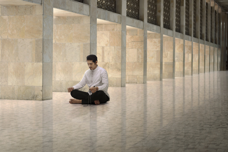 Religious asian muslim man with prayer beads praying in the mosqueの写真素材