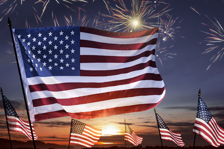 American flag on the sky waving celebrating 4th of July with fireworks backgroundの写真素材