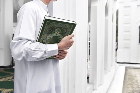 Muslim man hands holding the Koran in the mosqueの写真素材