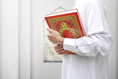Muslim man with traditional dress holding the Koran inside the mosqueの写真素材