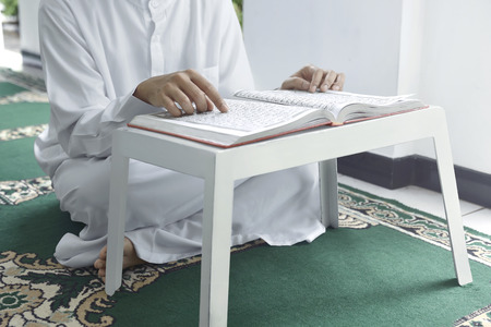 Muslim man sitting on carpet and reading the Koran in the mosqueの写真素材