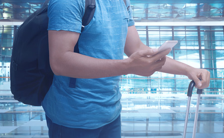 Man holding cellphone and suitcase. Travel concept imageの写真素材