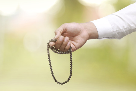 Muslim man praying with prayer beads over blur backgroundの写真素材