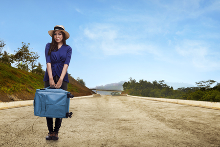 Pretty asian traveler with hat holding suitcase on the streetの写真素材