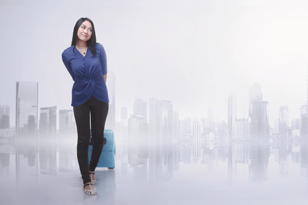 Happy asian woman traveling with suitcase against futuristic backgroundの写真素材