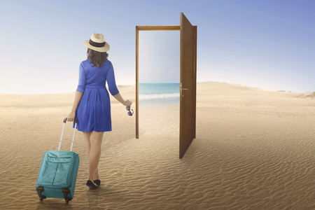 Tourist asian woman going to beach on the open door at desertの写真素材