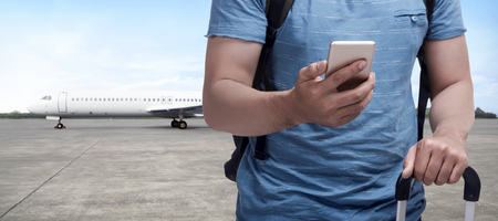 Backpacker asian man carrying bag with phone on his hand on runway airplaneの写真素材