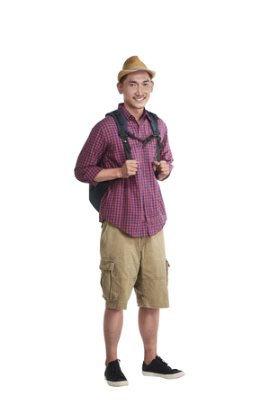 Happy asian traveler wearing hat with backpack standing over white backgroundの写真素材