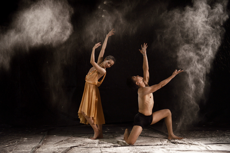 Beautiful couple ballet dancer with white powder explosion over black backgroundの写真素材