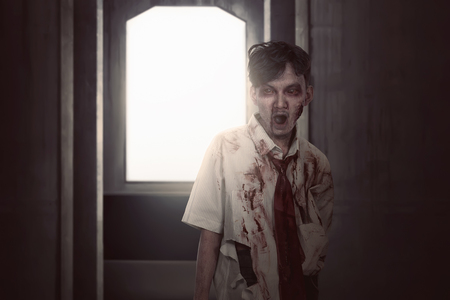 Scary asian zombie man in clothes standing on the dark roomの写真素材
