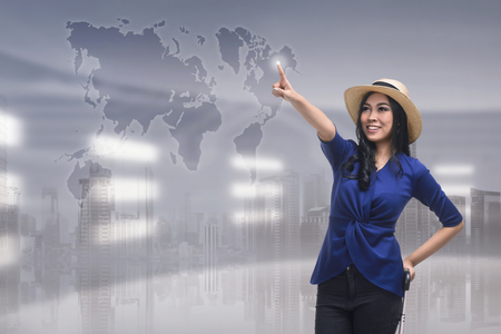 Beutiful asian woman touching travel destination on virtual screen over futuristic backgroundの写真素材