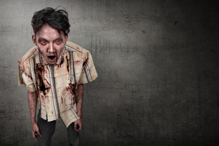 Scary and bloody asian zombie man against dark wall backgroundの写真素材