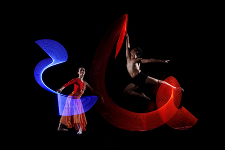 Attractive couple ballet dancer with colorful lights effect against black backgroundの写真素材