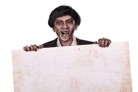 Portrait of asian zombie man holding empty white banner isolated over white backgroundの写真素材