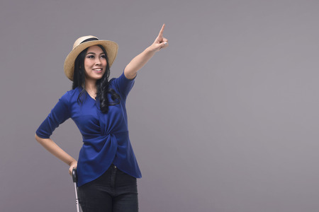 Portrait of asian woman tourist carrying suitcase against bright backgroundの写真素材