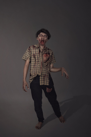 Horrible bloody asian zombie man against dark backgroundの写真素材