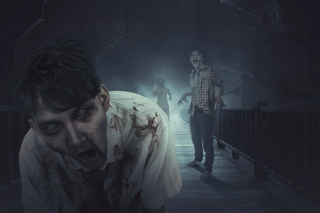 Crowd of asian zombies in clothes and blood on the dark forestの写真素材