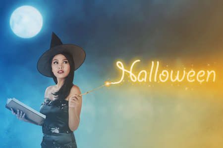 Young asian fairy woman with spellbook celebrate halloweenの写真素材