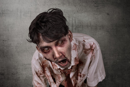 Portrait of scary asian zombie with wounded face against dirty wall backgroundの写真素材
